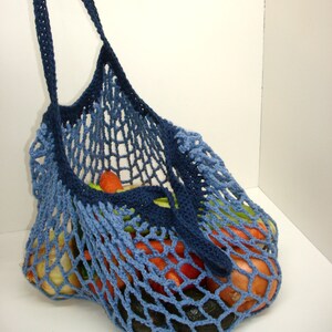May include: A blue crocheted mesh bag with a long handle, filled with vegetables, including carrots, onions, and celery.