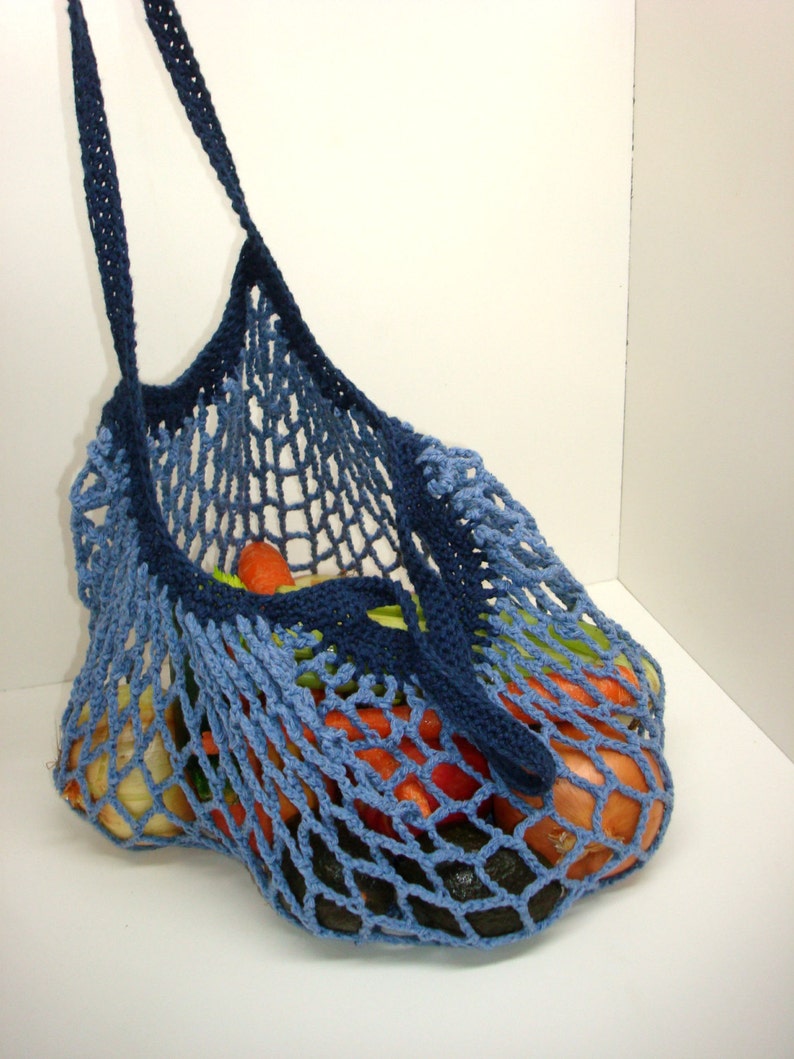 May include: A blue crocheted mesh bag with a long handle, filled with vegetables, including carrots, onions, and celery.