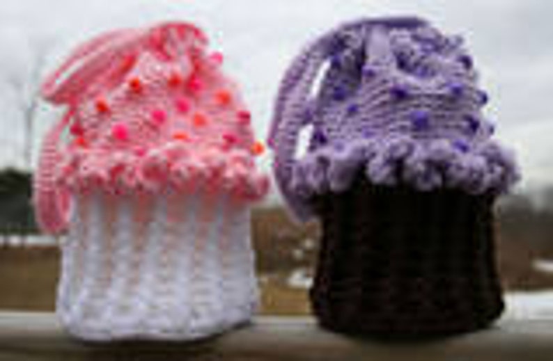 Peut inclure: Deux contenants en forme de cupcake crochet&eacute;s, l'un rose et blanc avec des pois roses et l'autre violet et noir avec des pois violets.