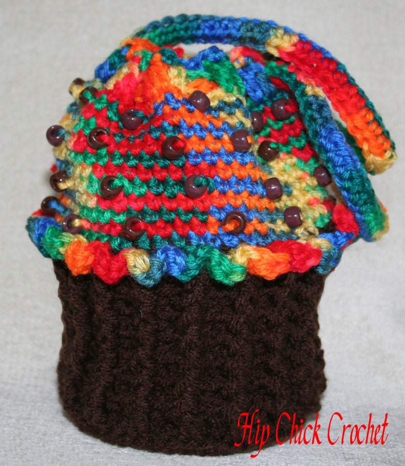Peut inclure: Un chapeau en crochet en forme de cupcake avec un motif ray&eacute; color&eacute; et des perles brunes. Le chapeau est fait d'un fil brun doux et a une base en crochet brun.