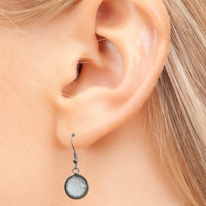 May include: Silver dangle earrings with a round, white, sparkly charm.