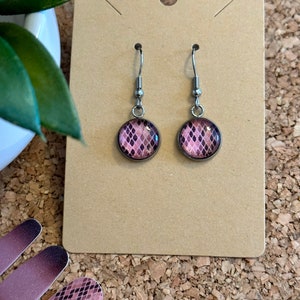 May include: A pair of silver dangle earrings with pink and black snake skin patterned glass cabochons.