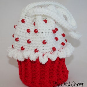 Peut inclure: Un sac en crochet blanc en forme de cupcake avec des perles rouges et une anse en crochet blanc. Le sac est rouge en bas et a un volant en crochet blanc autour du haut. Le texte "Hip Chick Crochet" est visible dans le coin inf&eacute;rieur droit de l'image.