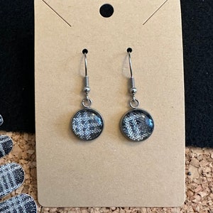 May include: A pair of silver earrings with round, black and white patterned glass cabochons.