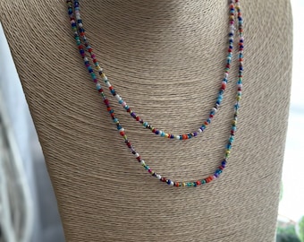 May include: A multi-layered necklace with small, colorful beads. The necklace is made of various colors, including red, blue, green, and white.