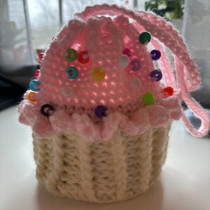 Peut inclure: Un coussin &agrave; &eacute;pingles en forme de cupcake crochet&eacute; avec un gla&ccedil;age rose et un moule &agrave; cupcake blanc. Le coussin est d&eacute;cor&eacute; de perles color&eacute;es.