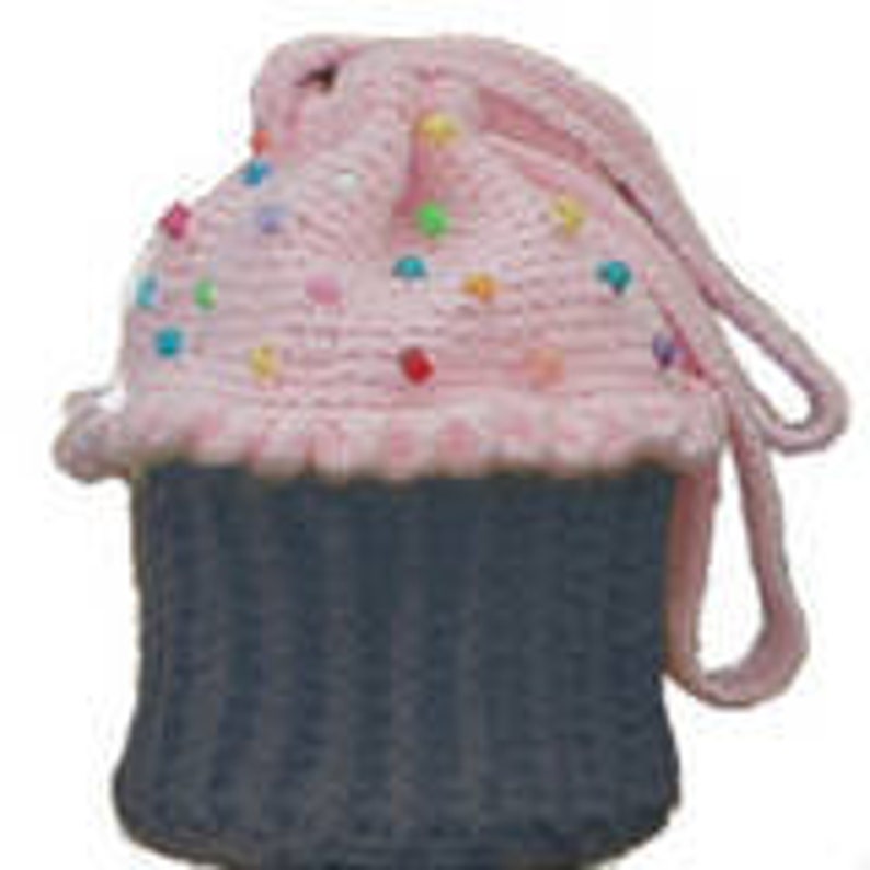 Peut inclure: Un sac &agrave; main en forme de cupcake crochet&eacute; rose et gris avec un motif de p&eacute;pites color&eacute;es. Le sac &agrave; main a une longue bandouli&egrave;re pour le porter.