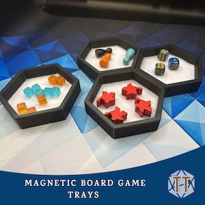 May include: Black hexagonal magnetic board game trays with white interiors, holding game pieces. The trays contain orange and blue dice, red player pieces, and game tokens. The text "MAGNETIC BOARD GAME TRAYS" is at the bottom.