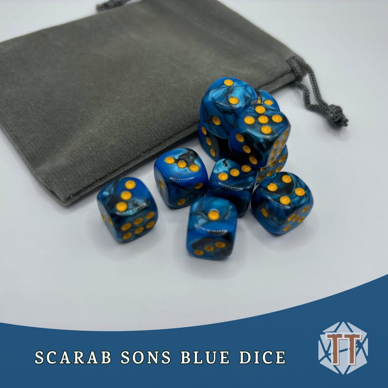 May include: A set of blue dice with yellow dots, in a gray velvet bag. The dice are marbled with black and blue swirls. The bag has a drawstring closure. The text "SCARAB SONS BLUE DICE" is visible at the bottom of the image.