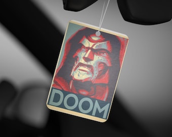 May include: A rectangular tag featuring a stylized portrait of a masked figure with the word "DOOM" in blue block letters. The portrait is set against a red and blue background, with a white string attached.