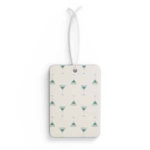 Puede incluir: Ambientador rectangular con un patrón repetido de copas de martini turquesas sobre un fondo crema. Tiene una cuerda blanca para colgar.