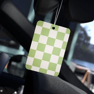 Puede incluir: Un ambientador de coche a cuadros verdes y blancos colgado del espejo retrovisor de un coche.