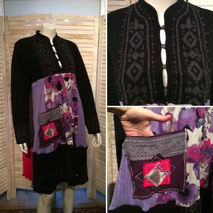May include: A black long-sleeved cardigan with a purple and floral patterned fabric underneath. The cardigan has a high collar and a button closure. The fabric underneath has a patchwork design with different textures and colors.