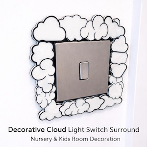 Könnte beinhalten: Eine dekorative Lichtschalterumrandung mit Wolkenmuster. Weiße Wolken mit schwarzen Umrissen umrahmen einen silbernen Lichtschalter. Der Text unten lautet "Decorative Cloud Light Switch Surround" und "Nursery & Kids Room Decoration."