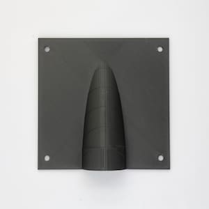 Puede incluir: Una placa de pared de plástico negro con un agujero redondo en el centro. El agujero tiene forma de cono y una superficie texturizada.