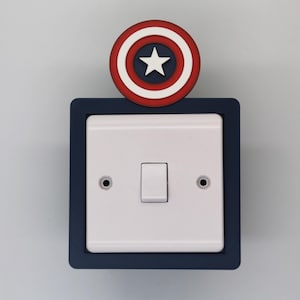 May include: A white light switch with a blue frame and a red, white, and blue star design on top.