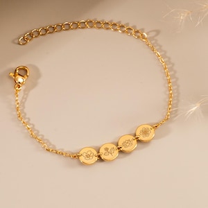 May include: A gold chain bracelet with four small round charms, each featuring a different floral design.
