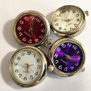 May include: Four small round quartz watches with silver bezels and different coloured faces. The faces are red, white, purple, and silver.