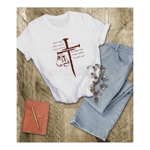 May include: White t-shirt with a brown cross and boxing gloves. The text on the shirt reads "There's days when a prayer won't cut it, and days when it takes all the strength I got."