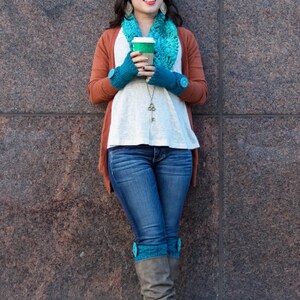 Puede incluir: Una mujer con un c&aacute;rdigan marr&oacute;n, una camisa blanca, pantalones vaqueros azules y botas marrones con polainas de punto turquesa. Est&aacute; sosteniendo una taza de caf&eacute; para llevar y mirando hacia arriba.