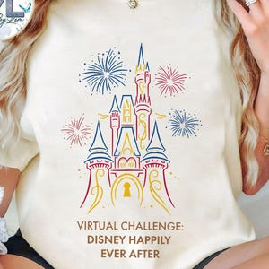 May include: Cream-colored t-shirt featuring a colorful line drawing of a castle with fireworks. The text "VIRTUAL CHALLENGE: DISNEY HAPPILY EVER AFTER" is printed below the castle design. The shirt has short sleeves.