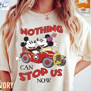 May include: Ivory-colored t-shirt featuring a vintage cartoon of Mickey and Minnie Mouse in a red car. The text "NOTHING CAN STOP US NOW" is printed in red. The shirt has a classic, relaxed fit.
