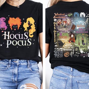 May include: Black t-shirt featuring the text "Hocus Pocus" with illustrations of the Sanderson sisters and stars. The back of the shirt has a collage of images and text related to the movie, including "I smell children" and "Amuck".