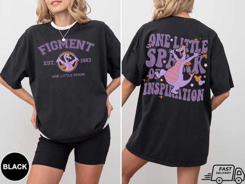 Op de afbeelding: Zwart T-shirt met een paarse draak afbeelding en de tekst "One Little Spark of Inspiration". De voorkant van het shirt heeft een paarse draak afbeelding en de tekst "Figment Est. 1983 One Little Spark".
