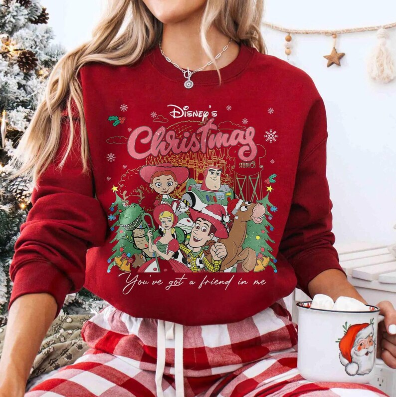 Może przedstawiać: Czerwona bluza z nadrukiem postaci z Toy Story Disneya, napisem "Disney's Christmas" i "You've got a friend in me". Bluza ma długie rękawy i okrągły dekolt.