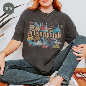 May include: A dark gray t-shirt with a colorful graphic of Disneyland park icons and the text "Disneyland Resort".