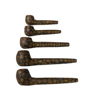 Puede incluir: Cinco pipas de fumar dispuestas en una pila vertical, cada una con un patrón floral moteado en marrón y bronceado en el hornillo y la boquilla. Las pipas varían en longitud, con la más corta arriba y la más larga abajo, mostrando un diseño de superficie texturizado.