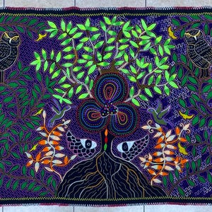 May include: A vibrant, hand-stitched textile featuring a central tree with green leaves and a multi-colored floral design. Two owls perch in the branches, with hummingbirds and snakes adding detail. The background is a deep purple with a black border.
