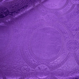 May include: Purple fabric with a paisley pattern. The fabric has a subtle sheen and a soft texture.