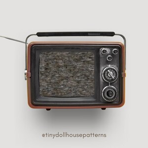 Op de afbeelding: Een vintage-stijl, bruin en zwarte televisie met een statisch scherm. De televisie heeft een zilveren knop en een zilveren antenne.