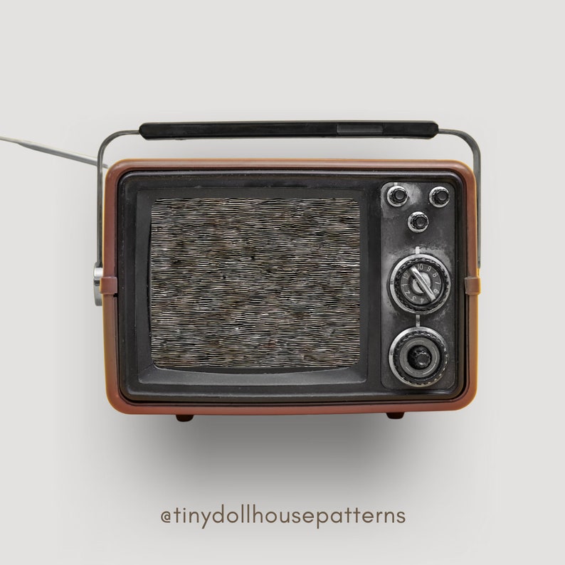 Op de afbeelding: Een vintage-stijl, bruin en zwarte televisie met een statisch scherm. De televisie heeft een zilveren knop en een zilveren antenne.