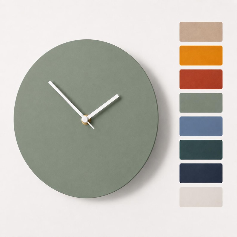 May include: A round sage green wall clock with white hour and minute hands and a small gold center cap. To the right, a vertical column displays eight rectangular color swatches in beige, orange, terracotta, sage, blue, teal, navy, and white.