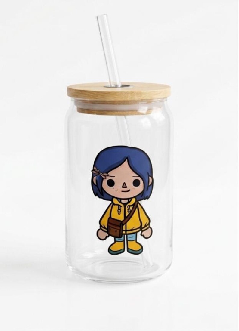 May include: A clear glass tumbler with a wooden lid and a clear straw. The tumbler features a cartoon illustration of a character with blue hair, a yellow jacket, and a brown bag. The tumbler is designed for cold drinks.
