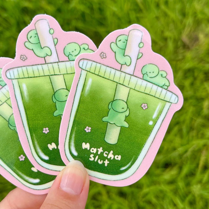 May include: Three stickers with a cartoon matcha drink design. The stickers have a pink border and the text "Matcha Slut". The drink is green with a straw and cute green characters.