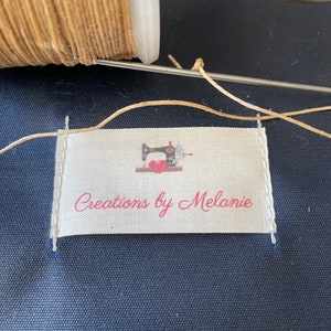 May include: A white fabric label with a red sewing machine and the text "Creations by Melanie".