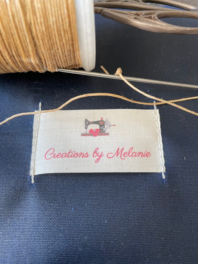May include: A white fabric label with a red sewing machine and the text "Creations by Melanie".
