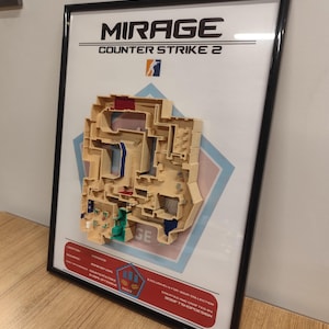 May include: A framed 3D map of the Mirage map from Counter-Strike 2. The map is made of beige plastic and shows the layout of the map with different colored rooms and corridors. The frame is black and has a white background with the text "MIRAGE" and "COUNTER STRIKE 2" in black.
