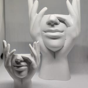 Peut inclure: Deux pots de fleurs blancs en céramique en forme de visage. Le plus grand présente un visage avec des mains couvrant les yeux, tandis que le plus petit a un design similaire. Les pots sont conçus pour contenir des plantes ou des fleurs.
