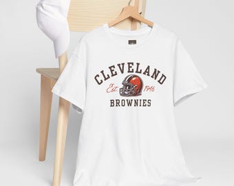 May include: White t-shirt with a brown and orange Cleveland Browns logo. The logo says "Cleveland Est. 1946 Browns".