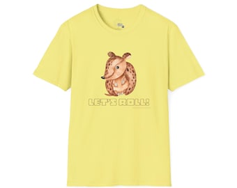以下が含まれることがあります： 薄い黄色のTシャツ。茶色の斑点のある漫画のアルマジロのイラストが描かれています。「LET'S ROLL！」の文字がアルマジロの下にブロック体で印刷されています。