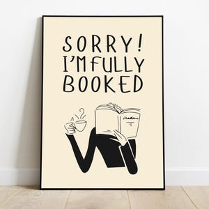 Puede incluir: Lámina artística enmarcada con el texto "SORRY! I'M FULLY BOOKED" en una fuente caprichosa. La ilustración muestra a una persona leyendo un libro y sosteniendo una taza de café. El fondo es de color beige claro.