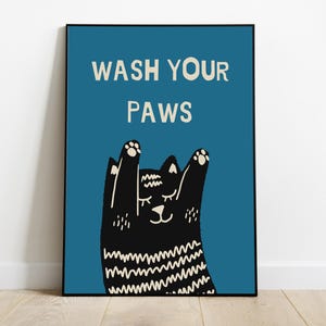 Op de afbeelding: Een blauwe poster met een zwarte kat met witte strepen en de tekst "WASH YOUR PAWS" in wit.