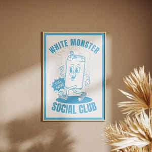 May include: A framed poster with a light blue cartoon design on a white background. The design features a walking soda can character with the text "WHITE MONSTER SOCIAL CLUB" and "STILL AWAKE". The frame is a light wood color.
