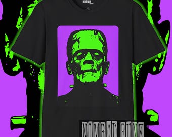 May include: Black t-shirt featuring a green and black graphic of Frankenstein's monster on a purple background. The design is framed within a purple rectangle. The text "NIMROD FUNK CREATIONS" is displayed at the bottom.