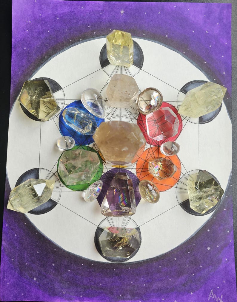 May include: A crystal grid with various clear, brown, and yellow crystals arranged in a geometric pattern on a white background with a purple border. The crystals are arranged in a circle with a star in the center.