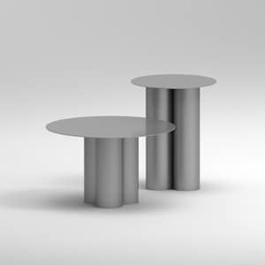 May include: Two modern, minimalist side tables in a light gray color. One table has a round top supported by three cylindrical legs. The other table has a round top supported by two cylindrical legs. The tables are set against a white background.